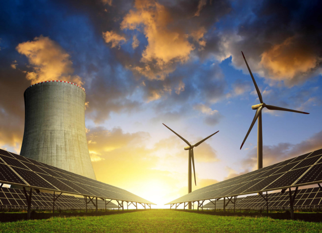 Solar energy panels before a nuclear power plant and wind turbines at sunset